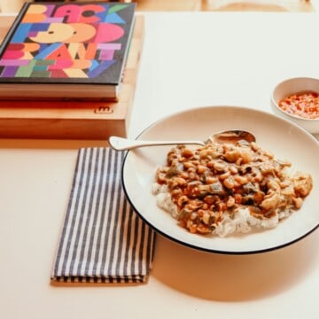 Black Food cookbook, a bowl of vegetarian gumbo, a napkin, and a small bowl of piri piri sauce