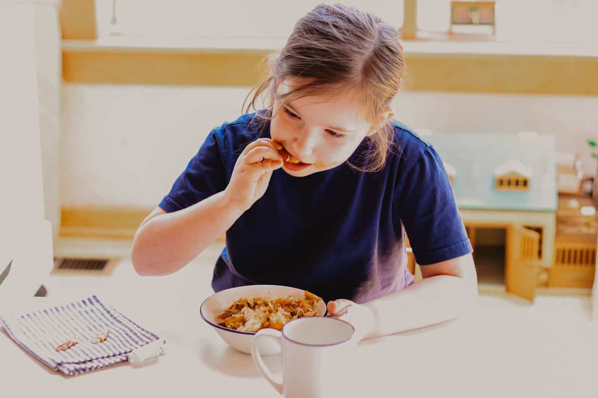 child sitting at a table and eating Persian rice and shrimp
