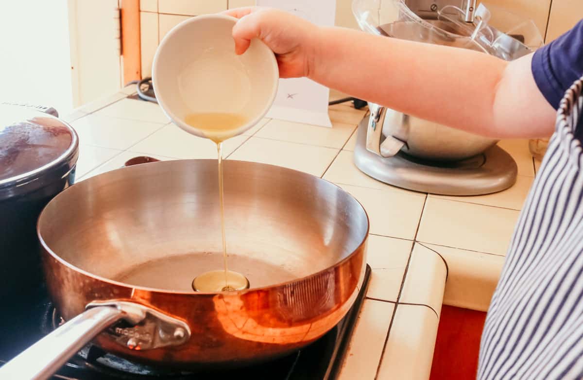 child adding oil to a copper saucier