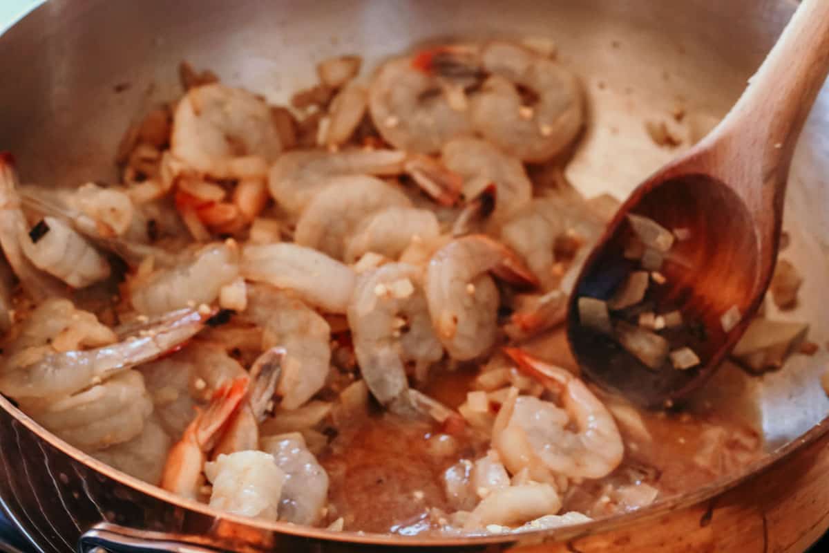 raw shrimp cooking in a copper saucier