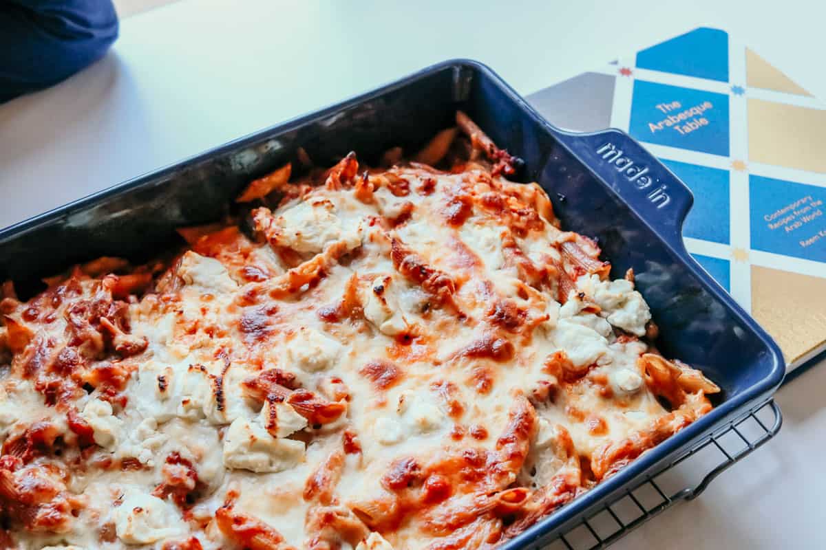 Goat Cheese Pasta Bake in a Blue Made In Rectangular Baking Dish next to The Arabesque Table cookbook