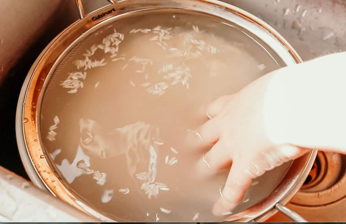 closeup of child washing rice with their hand