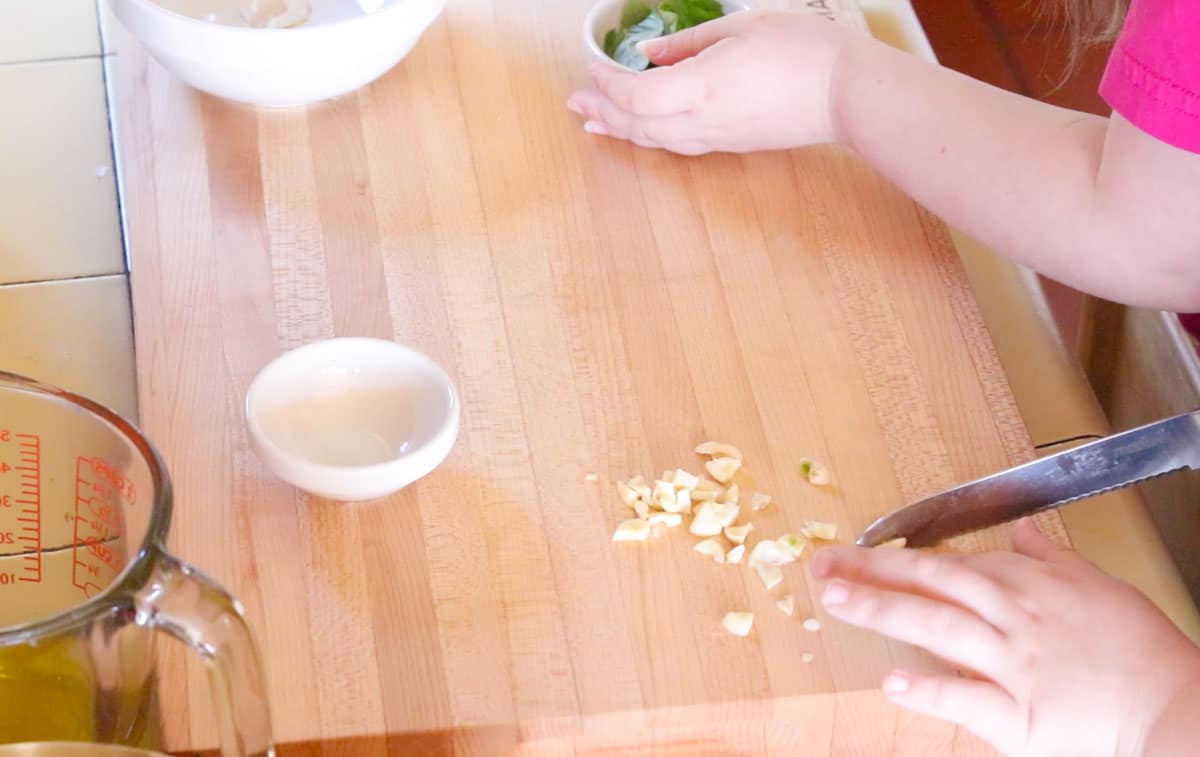 Noah is using a utility knife to chop the garlic