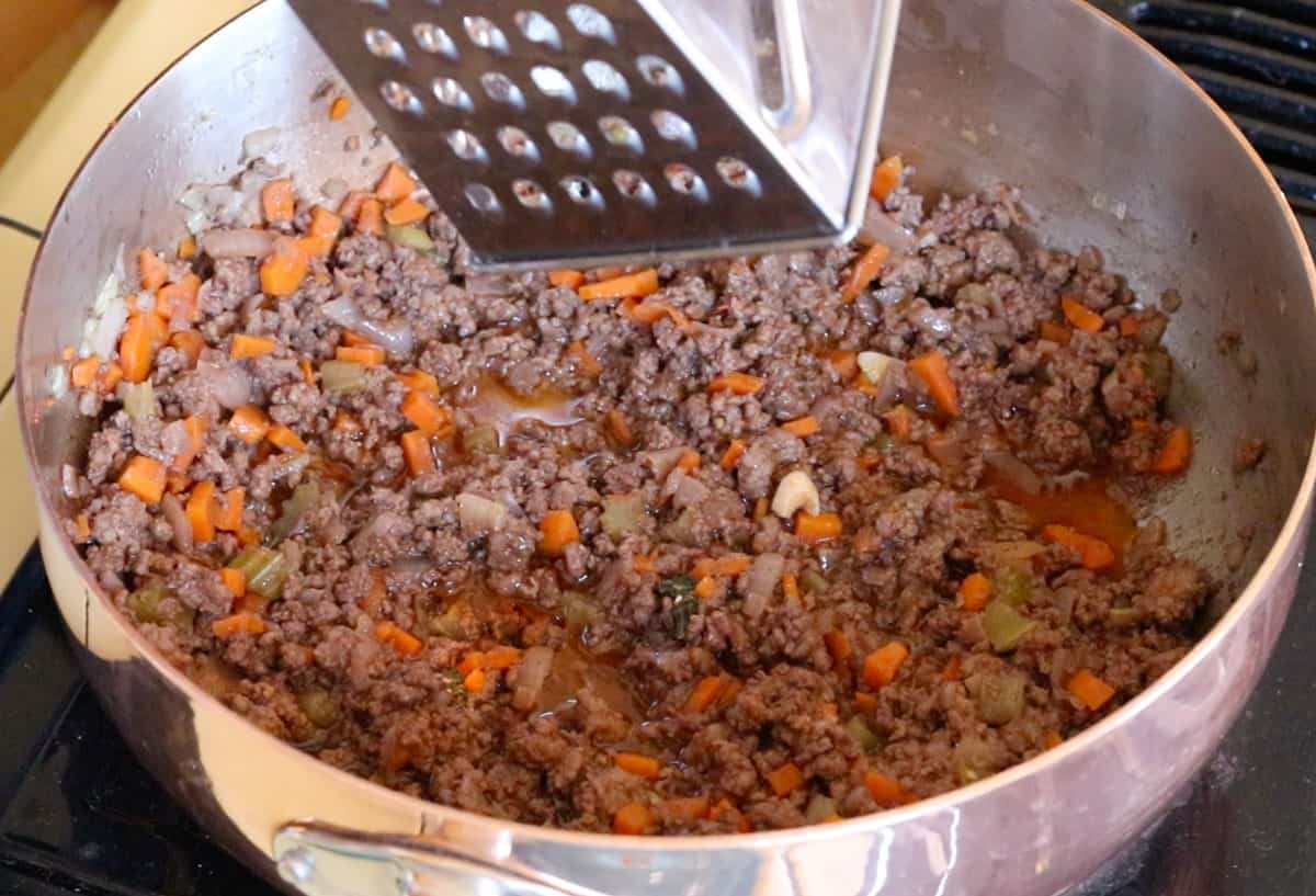 grating nutmeg over saucier for bison bolognese