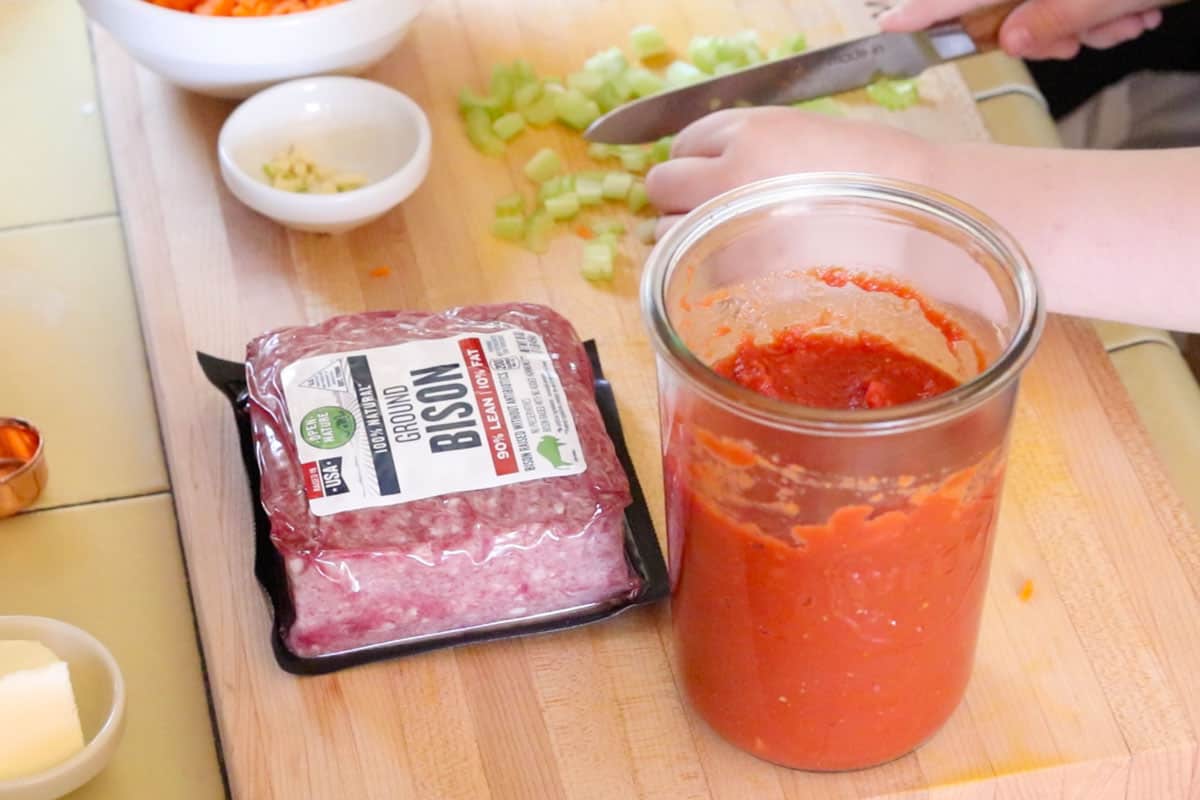 ground bison, homemade tomato sauce, and Noah chopping celery