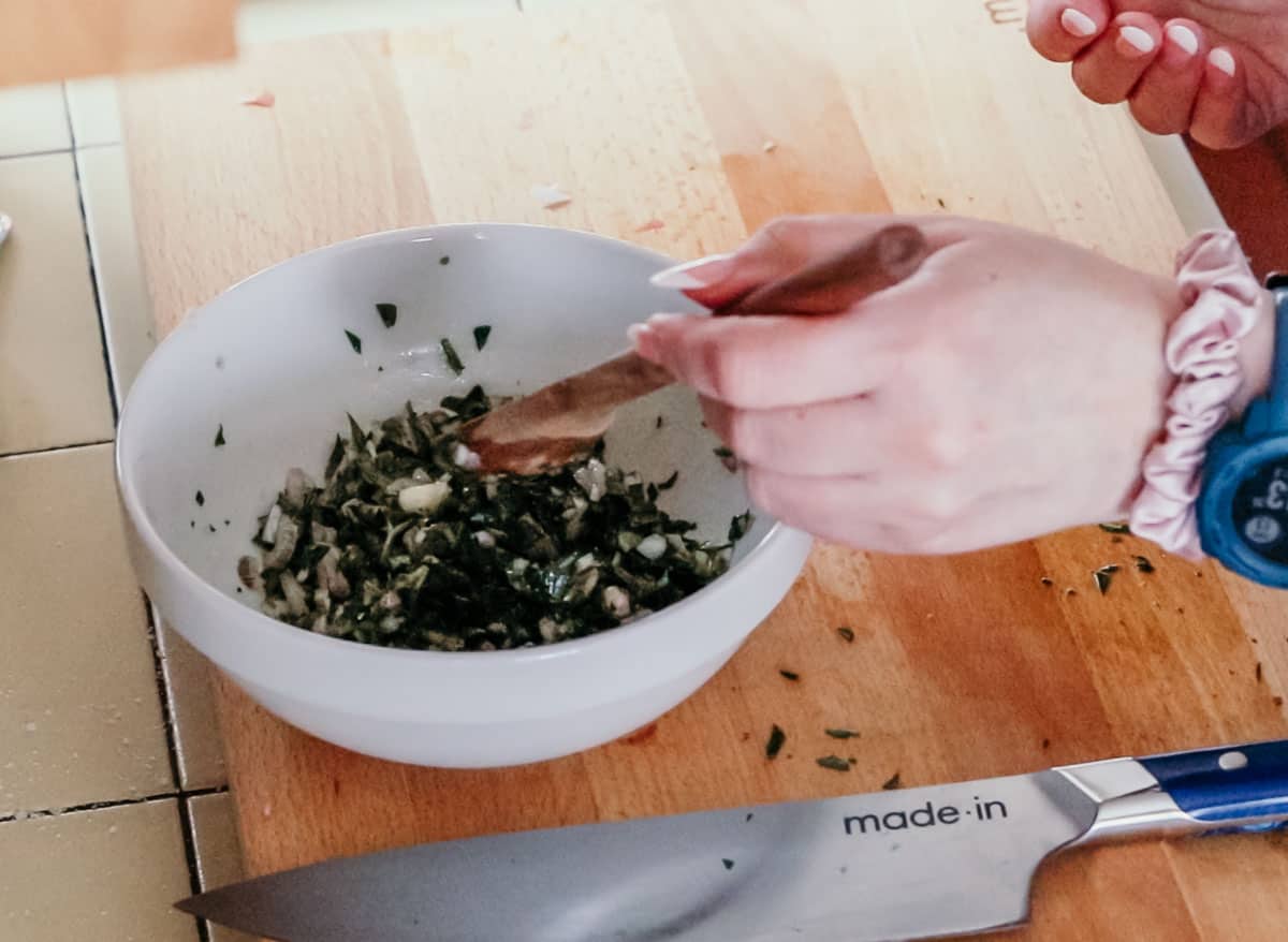 stirring salsa verde with a wooden spoon