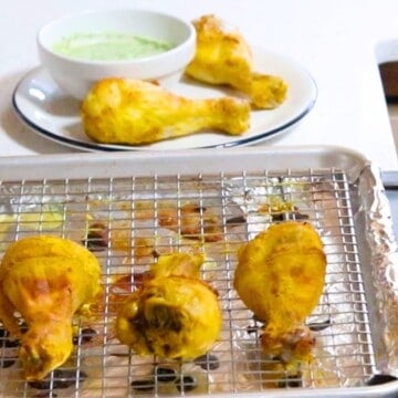 tandoori chicken drumsticks on a cooling rack and on a plate with dipping sauce