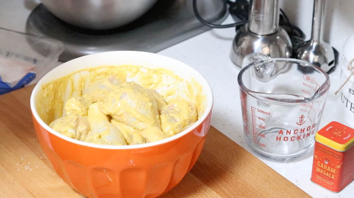 chicken drumsticks marinating in a yogurt-based marinade