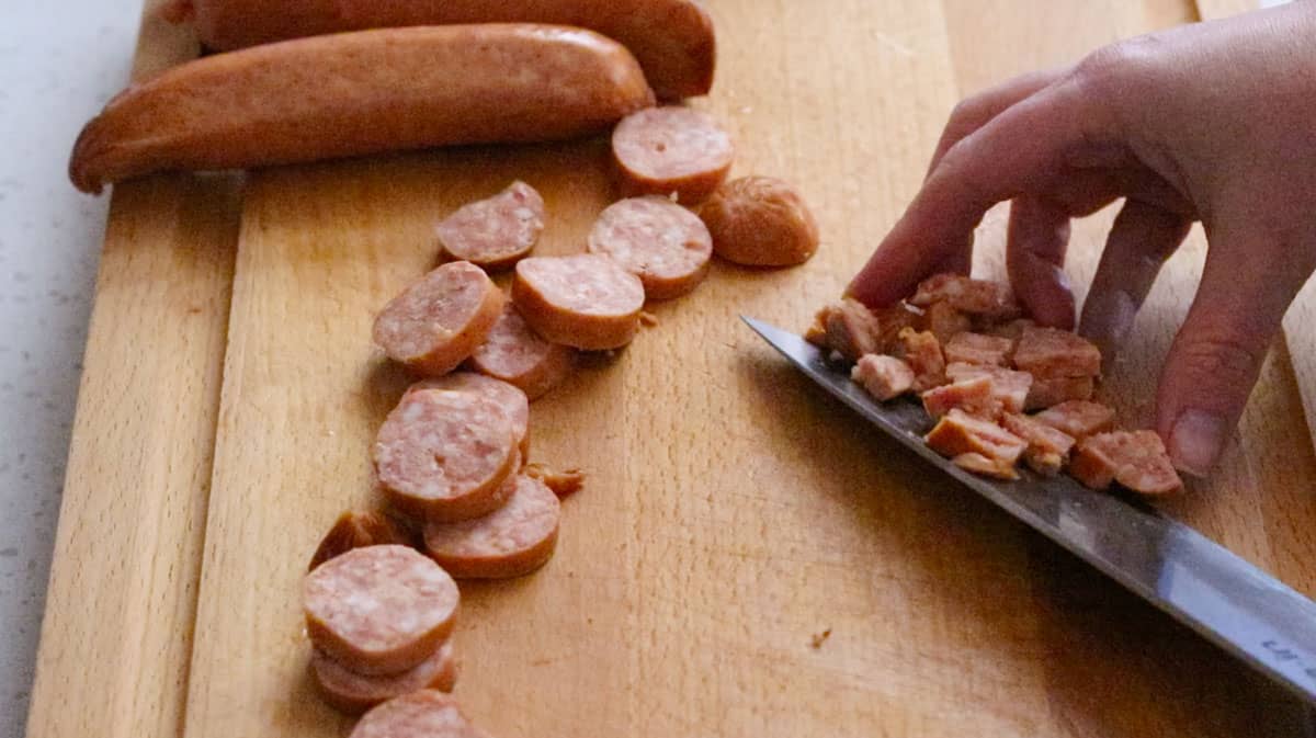cutting up kielbasa ingredients using a knife and butcherblock