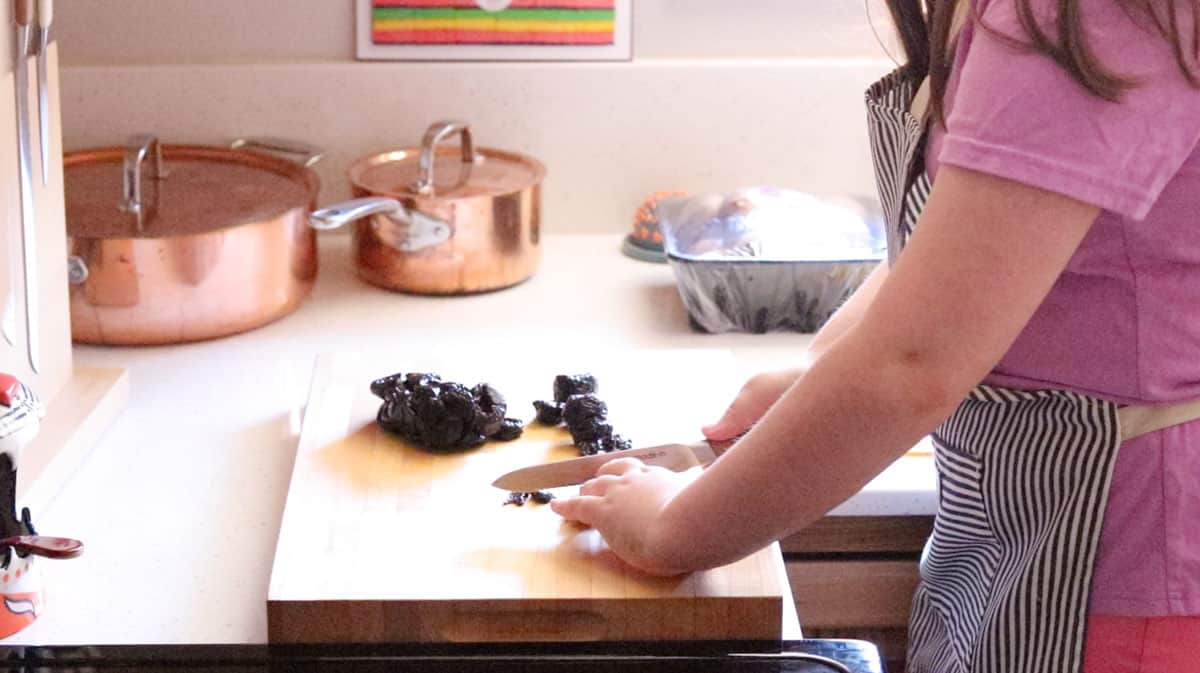 Kaia is chopping prunes on a butcher block