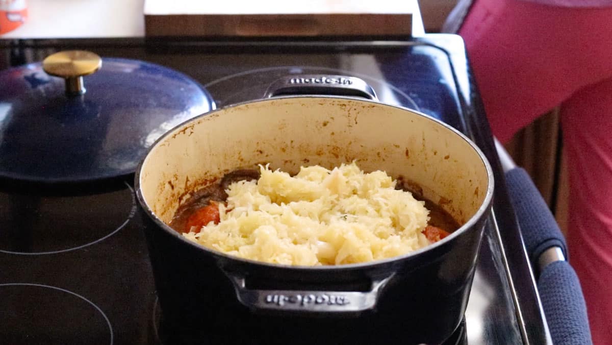 sauerkraut on top of bigos in a Dutch oven