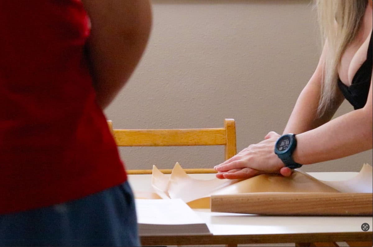 Kristin is flattening the dough with her hands for the kids