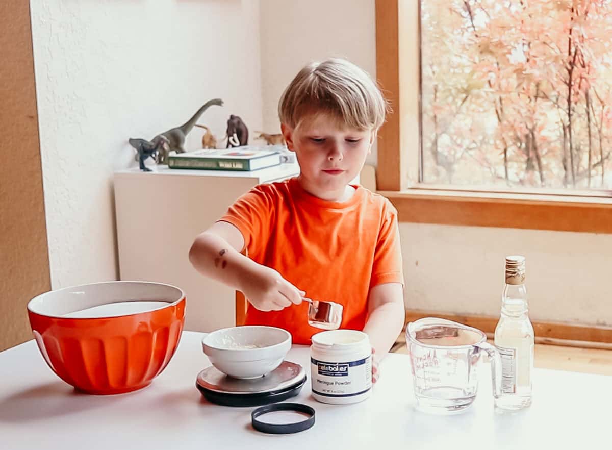 Noah is adding meringue powder to a bowl