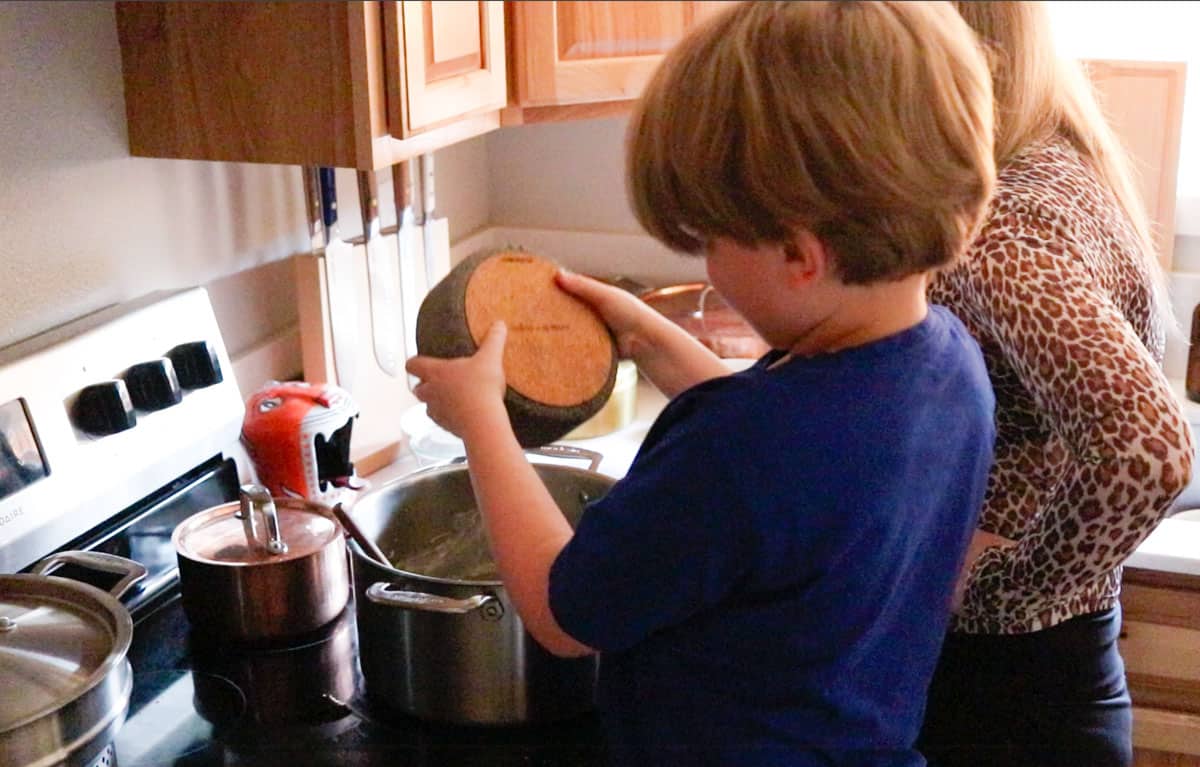 Noah is adding freshly ground pepper to a stock pot