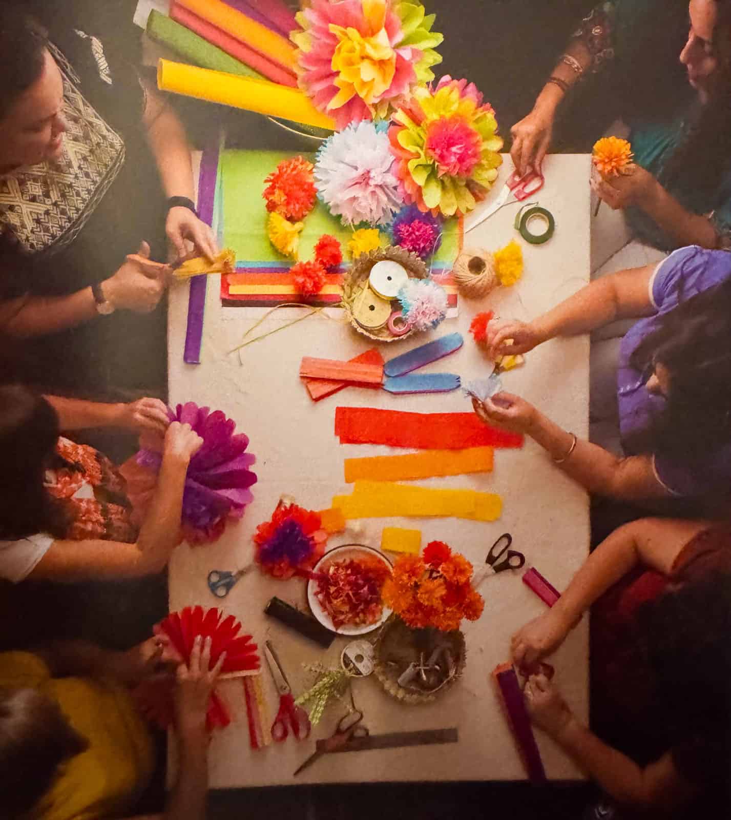 people gathered around a table making tissue paper flowers