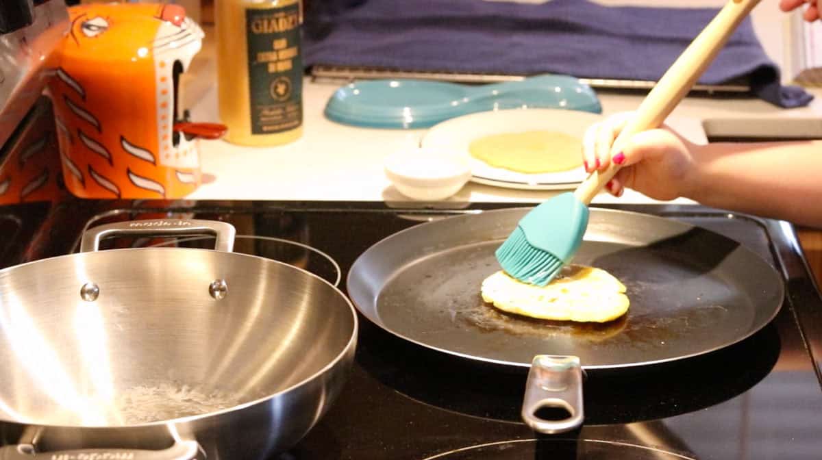 Katalina is brushing the parathas with olive oil using a pastry brush