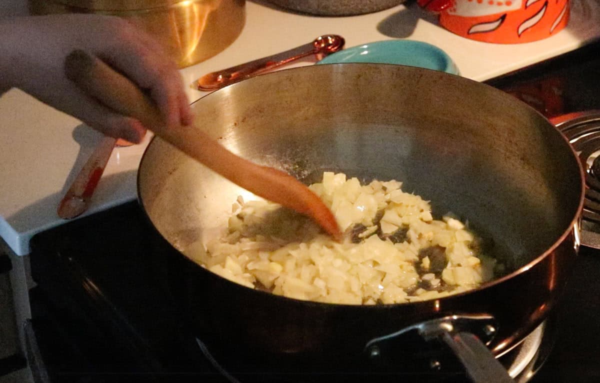 Noah is cooking garlic and onions in a saucier