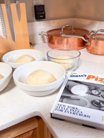 4 dough balls in bowls beside Giadzy extra-virgin olive oil and The Scarr's Pizza Cookbook: New York-Style Pizza for Everybody