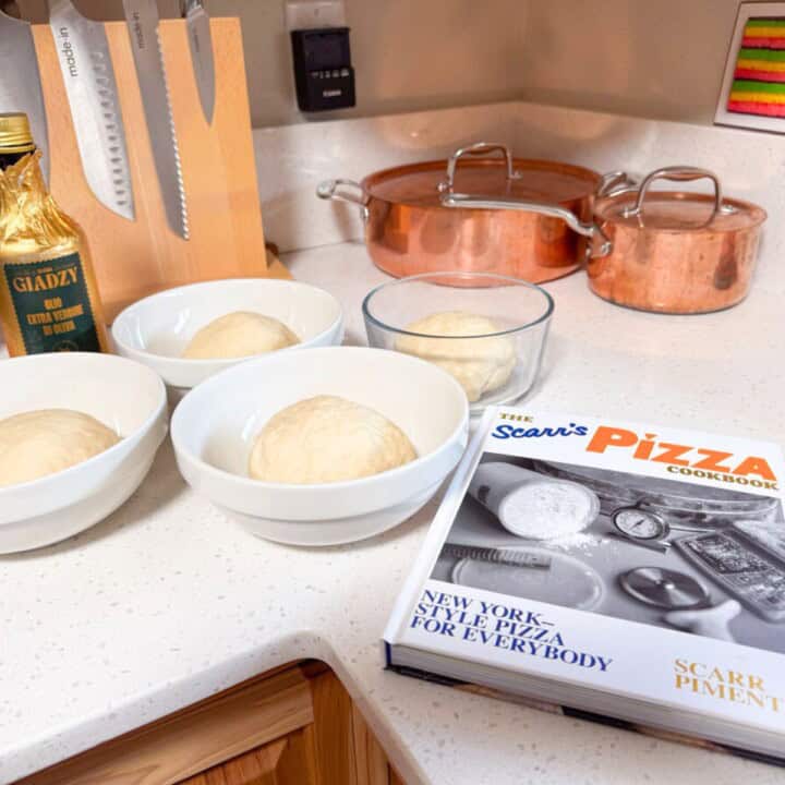 4 dough balls in bowls beside Giadzy extra-virgin olive oil and The Scarr's Pizza Cookbook: New York-Style Pizza for Everybody