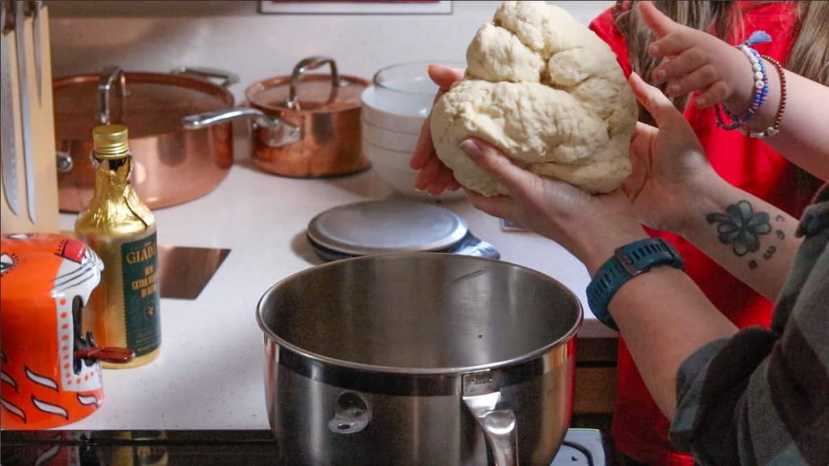 taking dough out of a mixing bowl