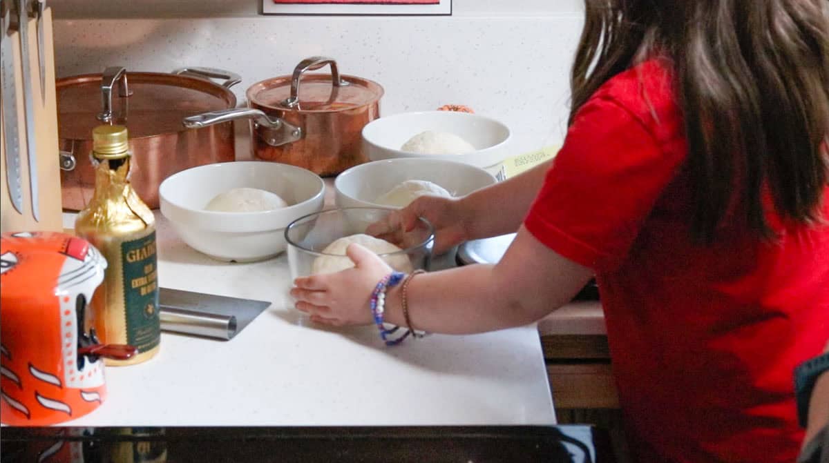 Katalina is holding a container with a dough ball in it