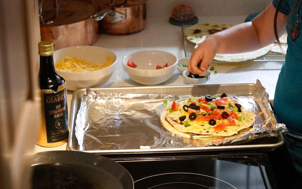 Katalina is sprinkling toppings on a mexican pizza