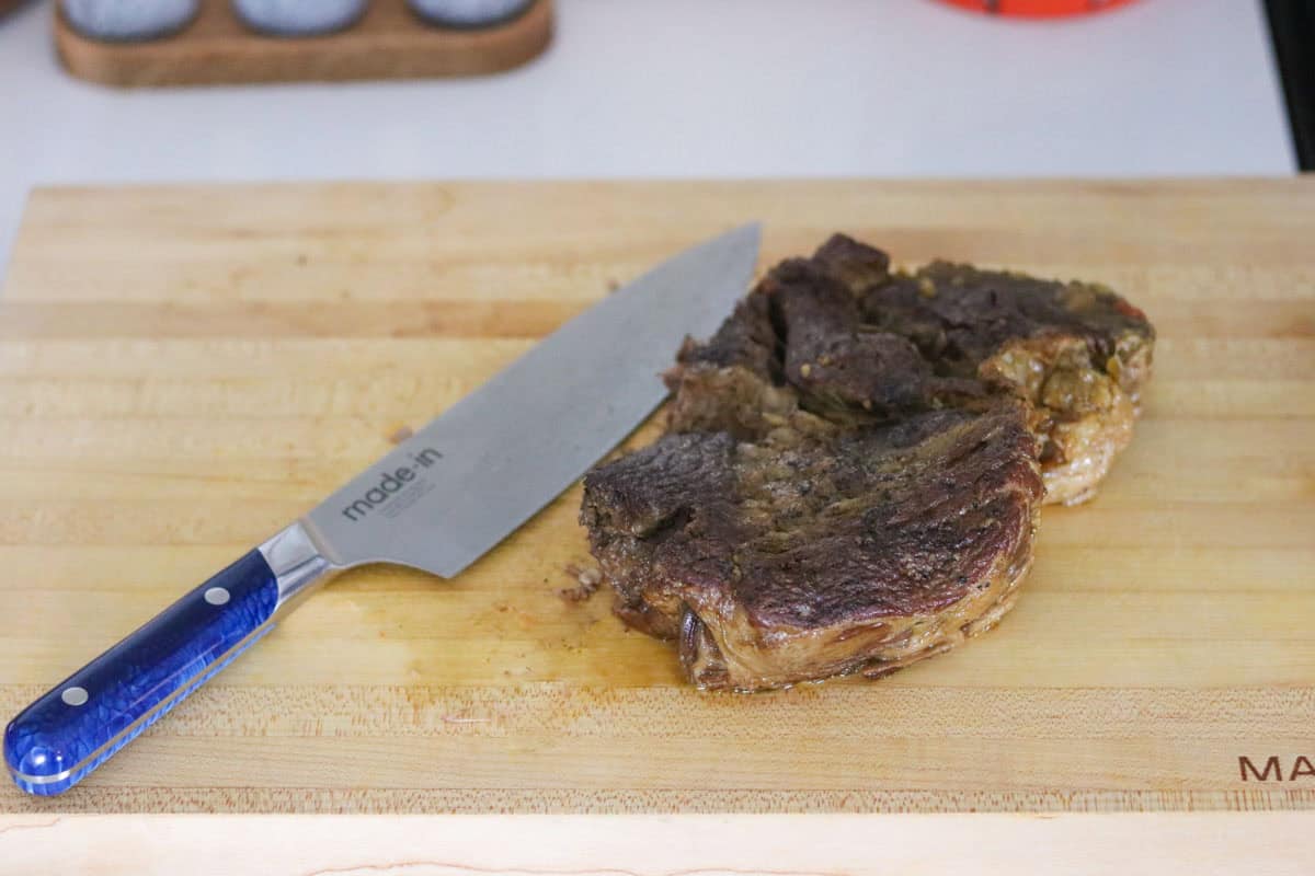 braised beef on a butcher block beside a chef knife
