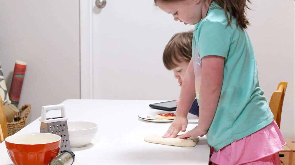 Katalina is pressing on her pizza dough, John is eating pizza his way - undercooked