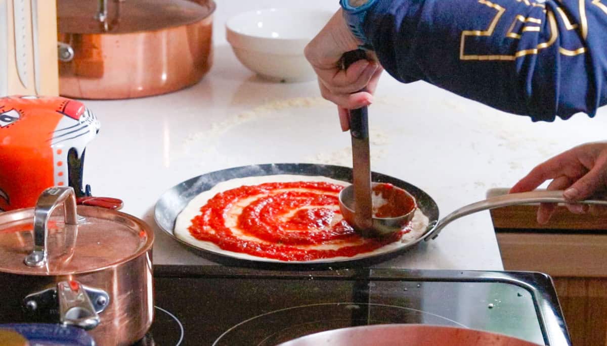 ladling sauce on pizza