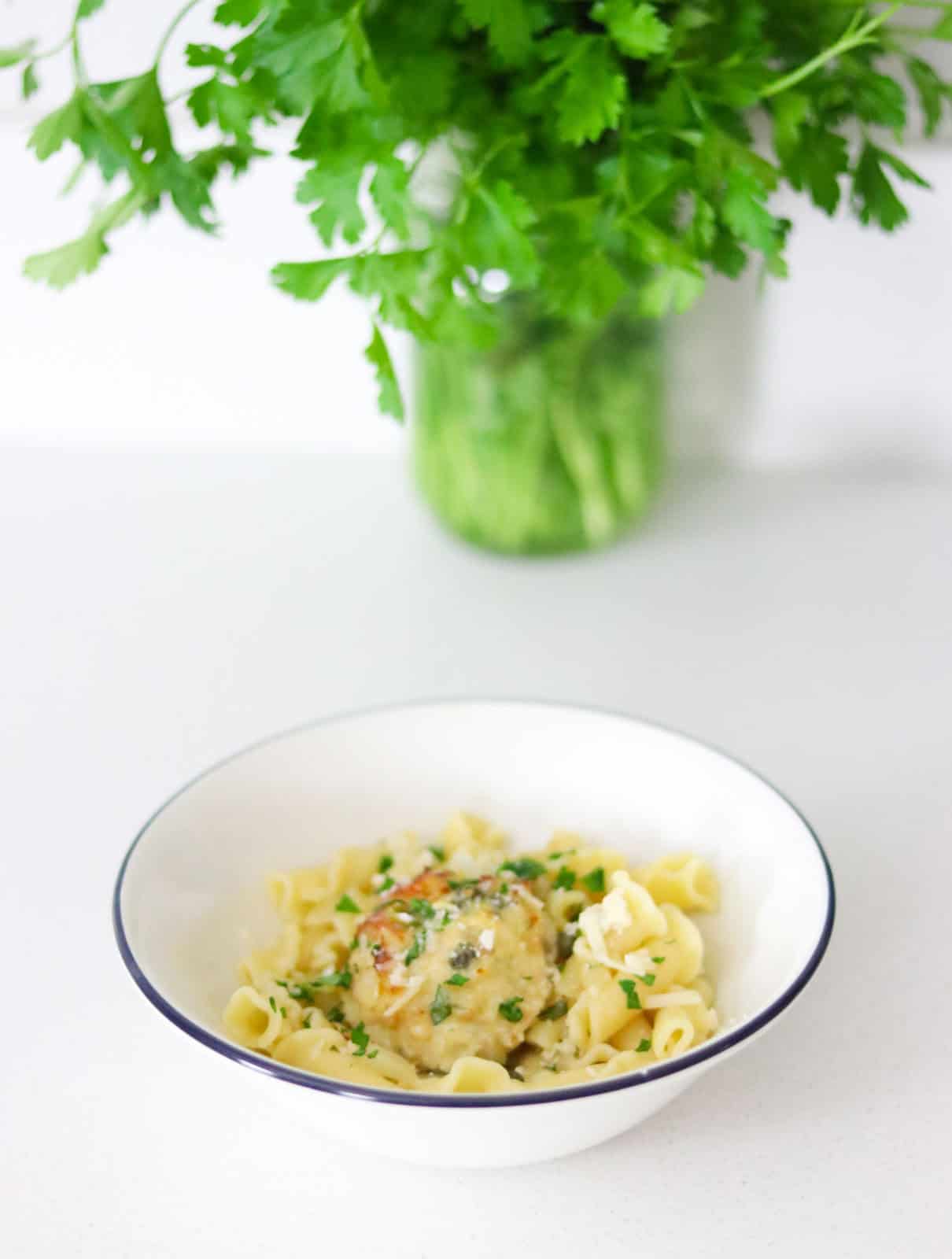 chicken piccata meatball over a bed of campanelle, topped with parsley and Parmigiano-Reggiano