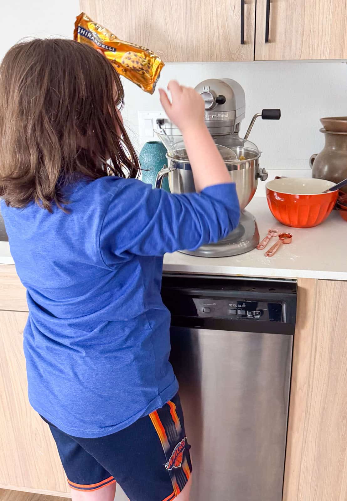 Kaia is adding chocolate chips to the stand mixer