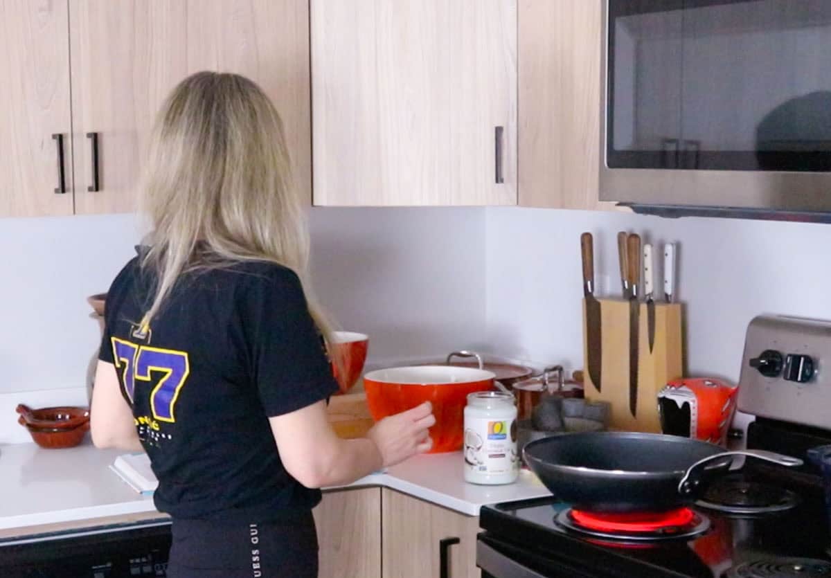 Kristin is preparing the wok for the chicken wings by adding coconut oil