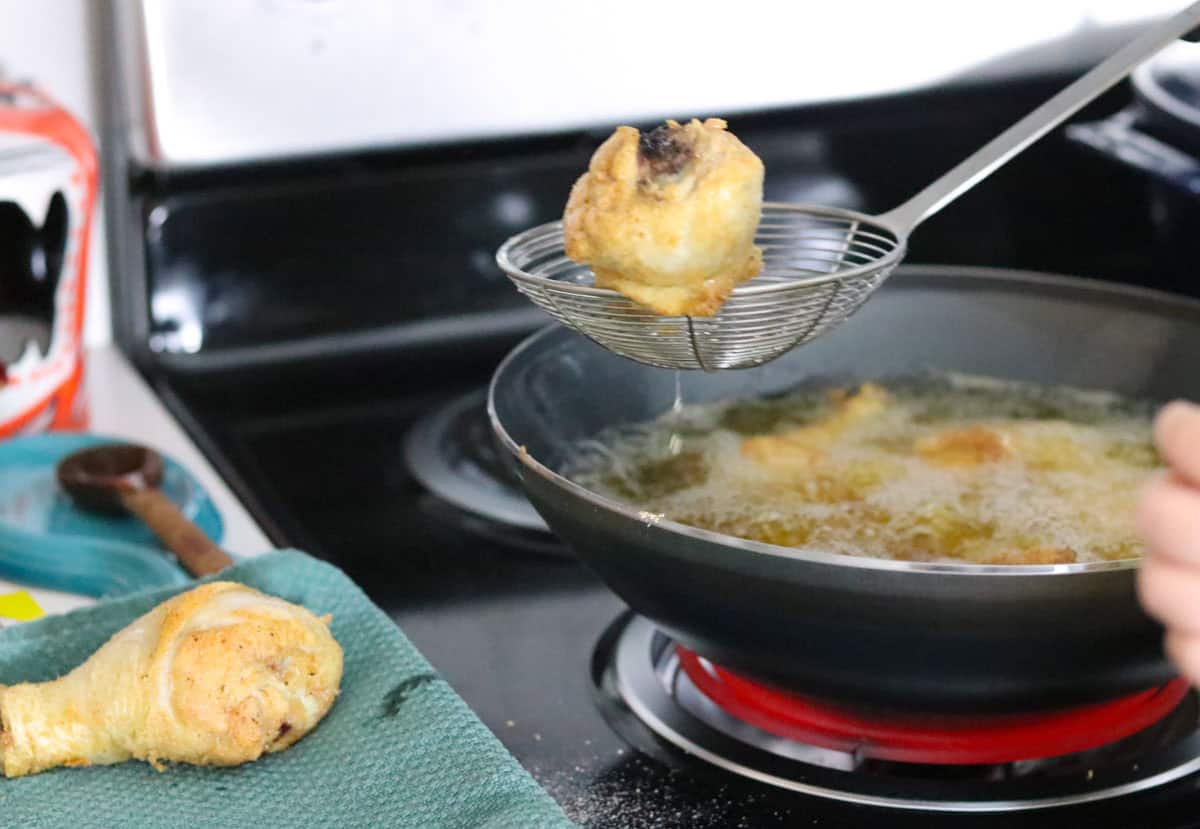 chicken drumstick in a spider strainer over a wok