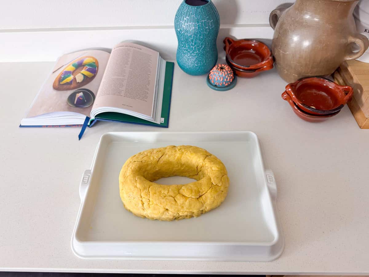 unbaked king cake on a baking slab beside an image of king cake from Recipes from the American South