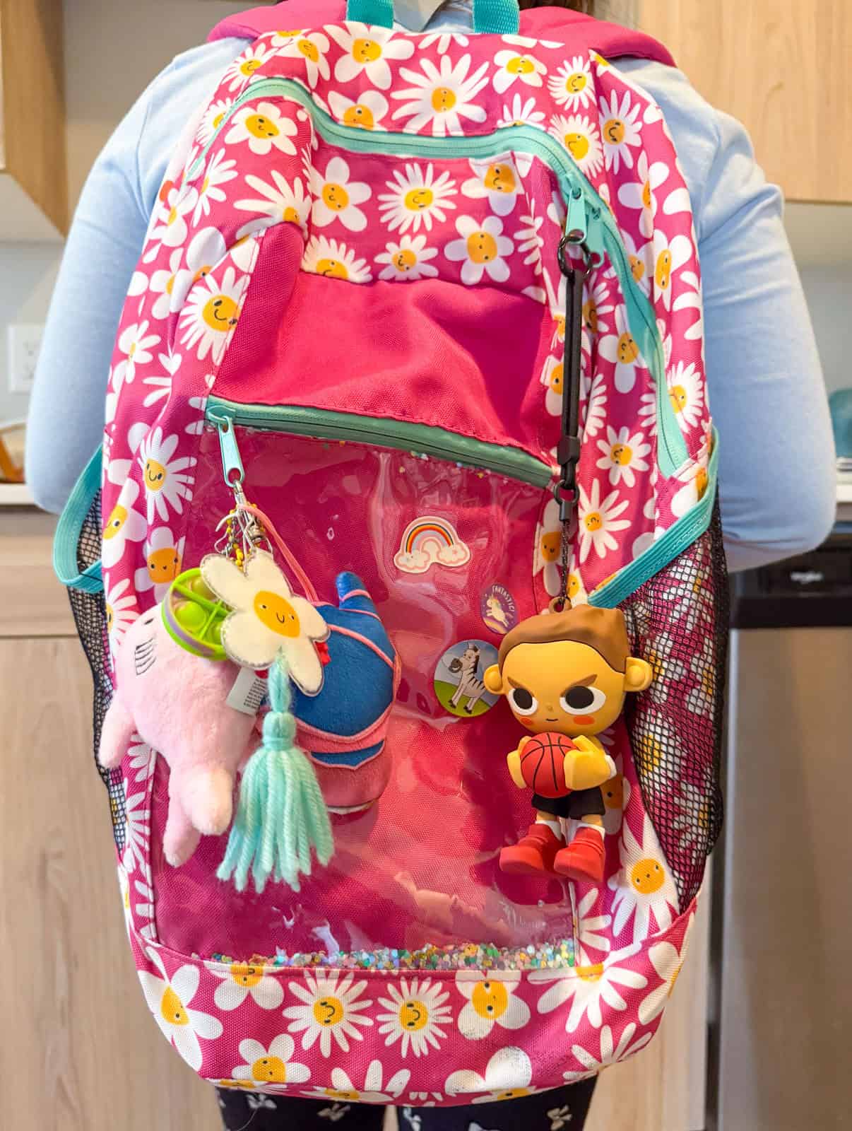a child's pink,flowery backpack with keychains attached