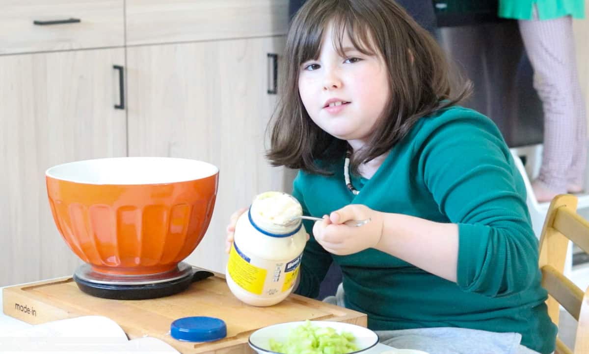 Kaia is scooping mayo out of a jar with a spoon