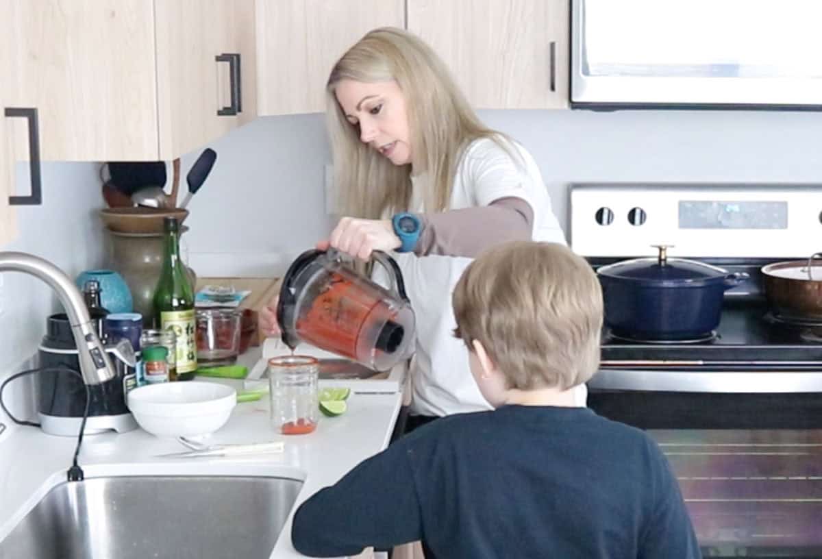 Kristin is pouring bloody mary mix into a mason jar
