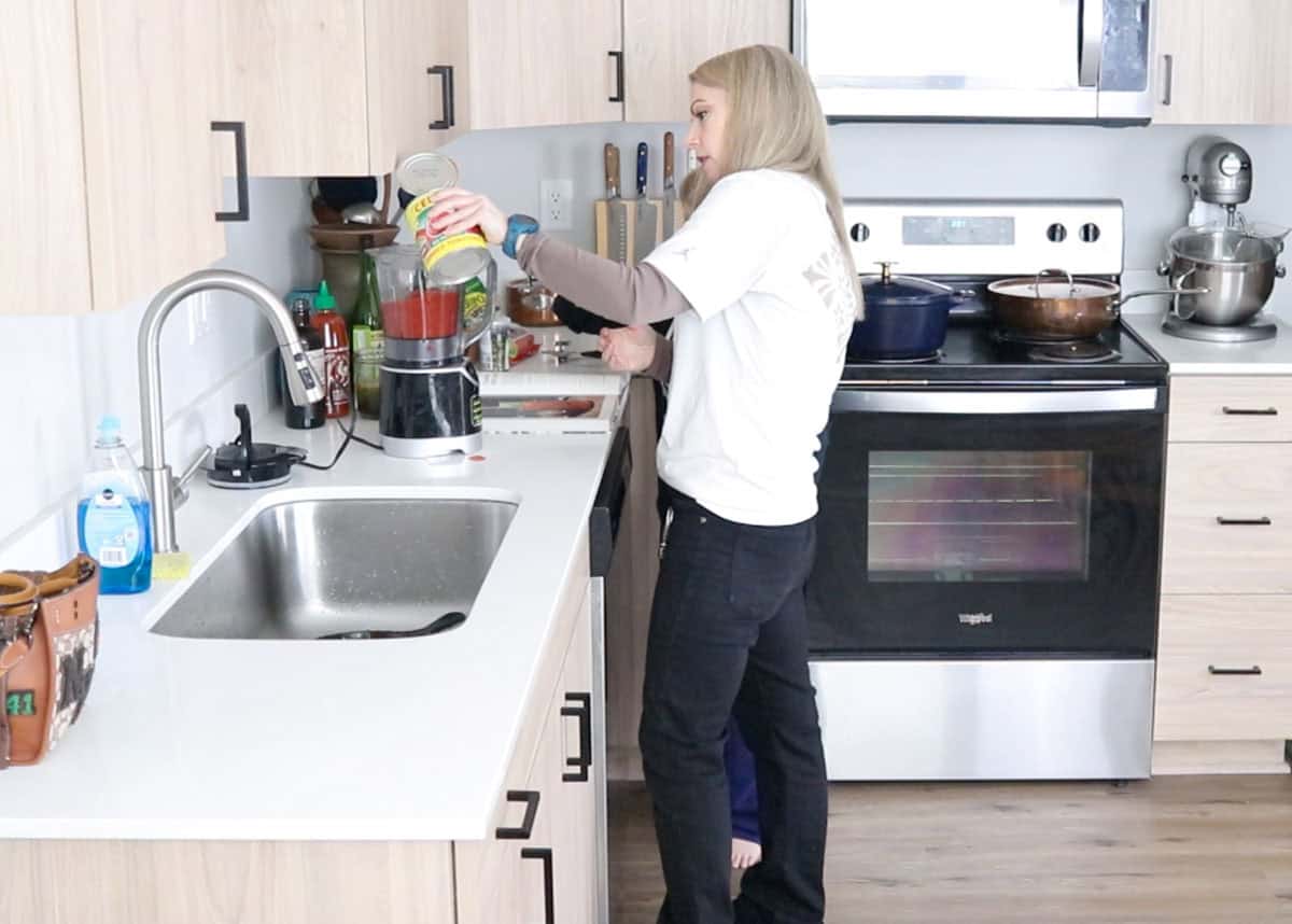 Kristin is adding crushed tomatoes to a blender