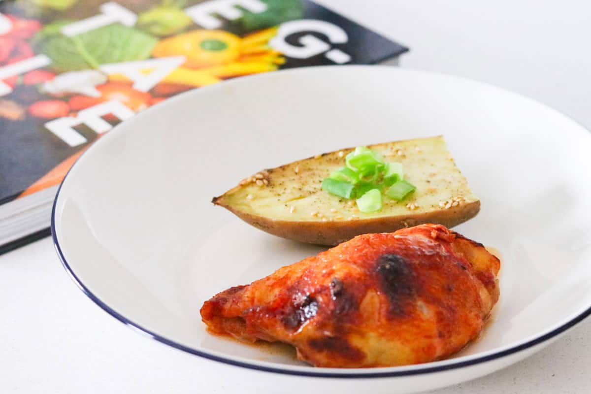 gochujang chicken and sesame sweet potato plated beside Veg-Table cookbook