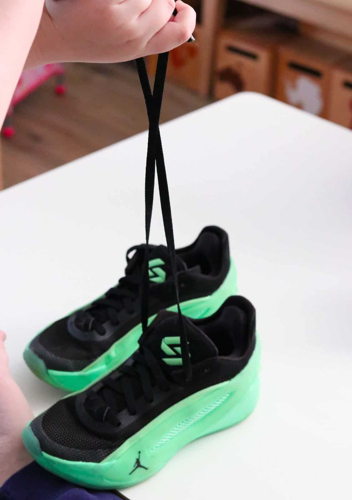 Noah is holding the ends of his laces and crossing them over