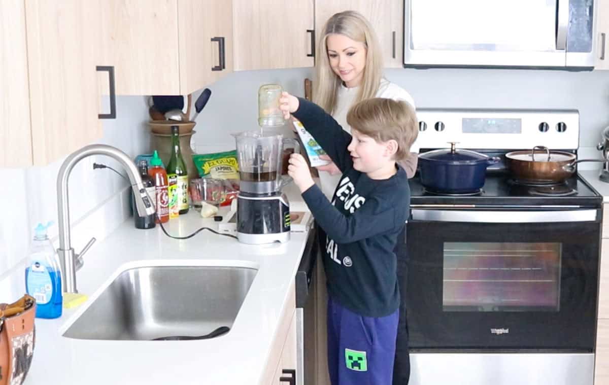 Noah is adding olive oil to a blender