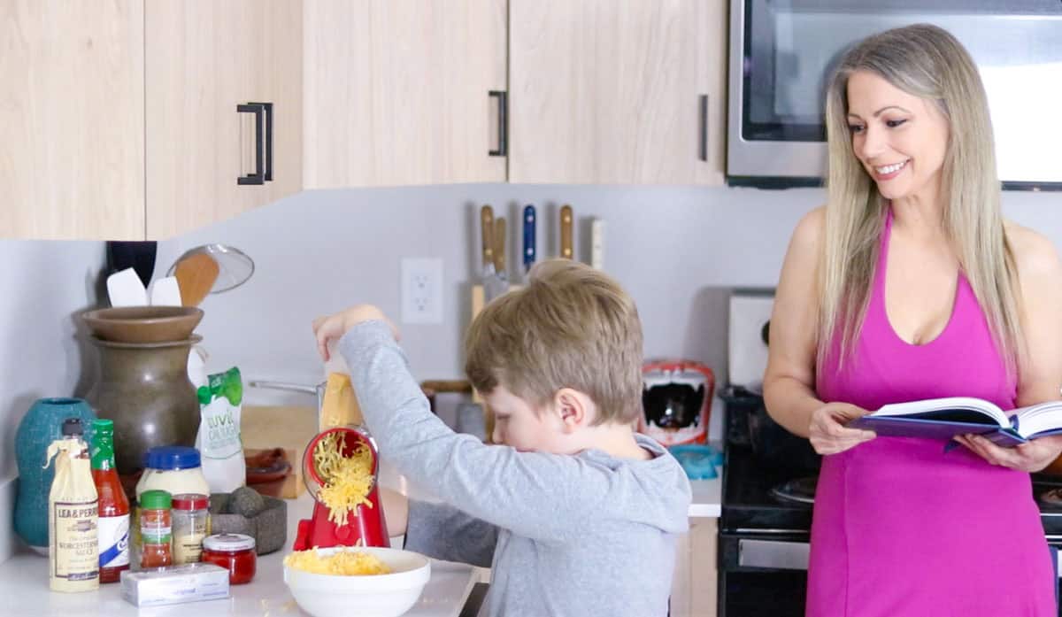Noah is grating cheddar cheese into a bowl at the kitchen counter