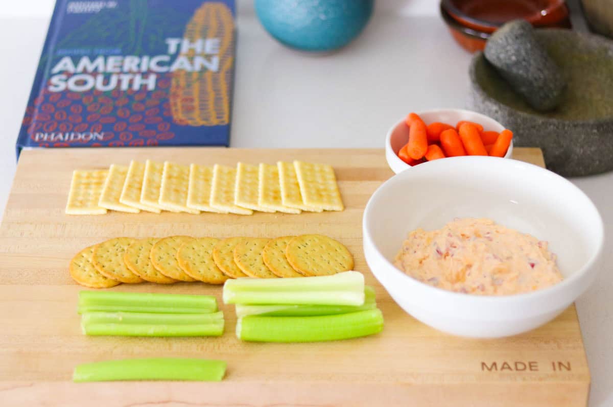 Recipes from the American South, butcher block with crackers, celery, and carrots, and pimento cheese in a bowl