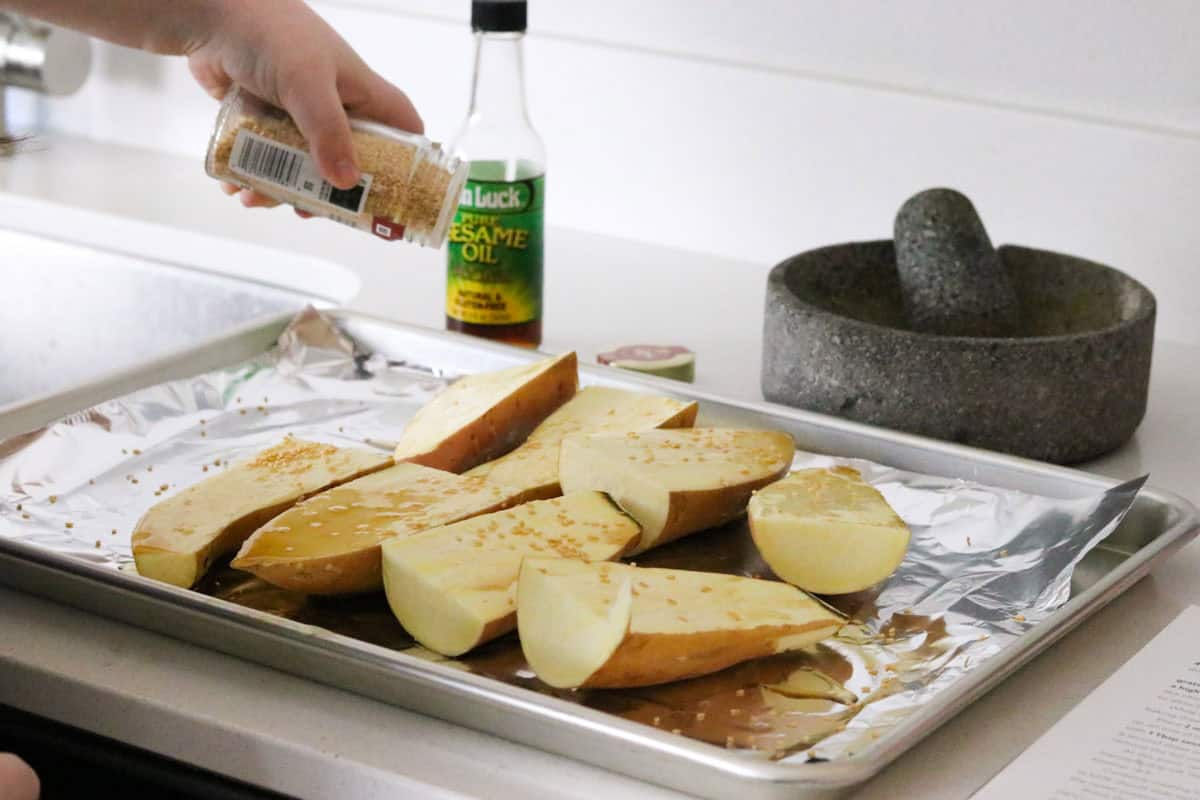 Kaia is topping sweet potatoes with sesame seeds