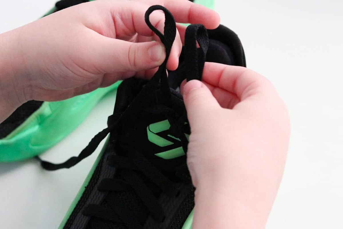 Noah is creating a second loop to tie his Jordan Luka 5 Venom basketball sneakers