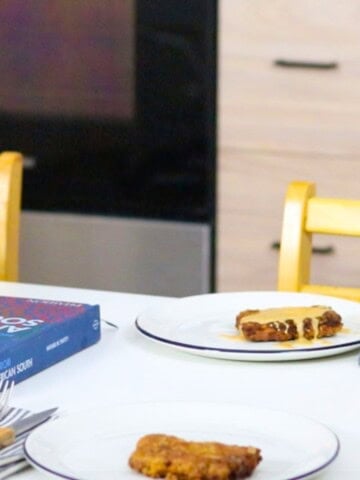 plated chicken-fried steak with pan gravy at the table beside Recipes from the American South