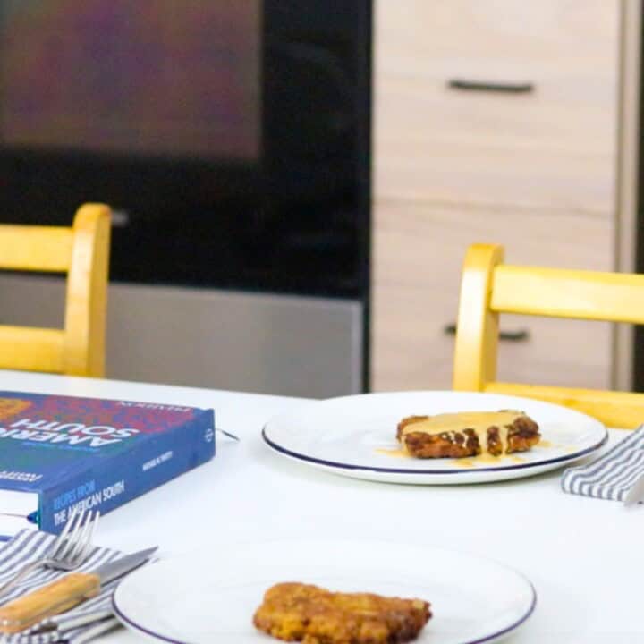 plated chicken-fried steak with pan gravy at the table beside Recipes from the American South