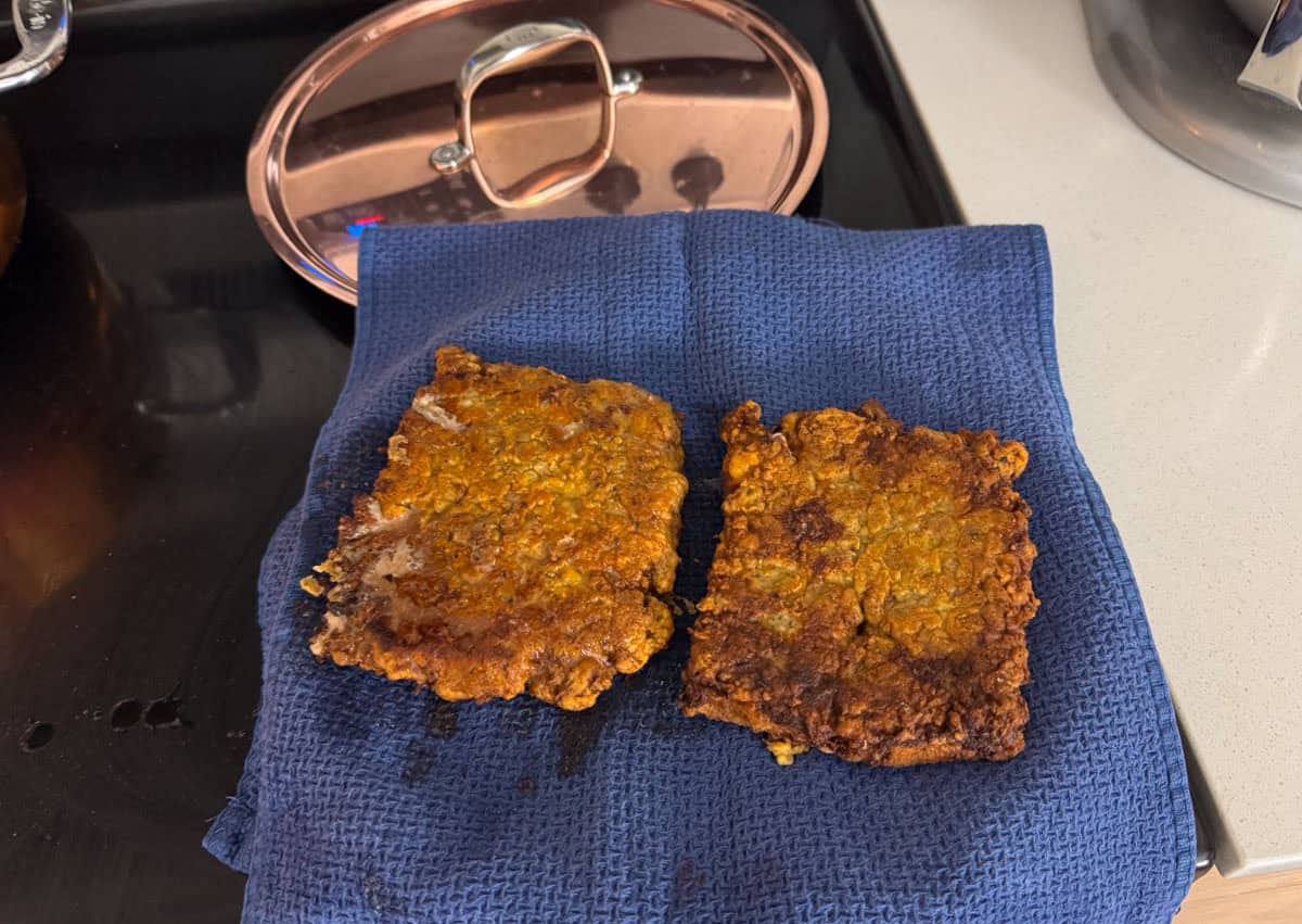 cube steaks draining on a plate lined with a kitchen towel