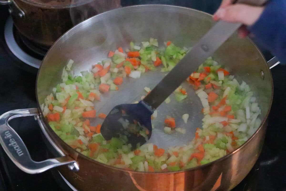 Katalina is stirring cooked vegetables in a rondeau