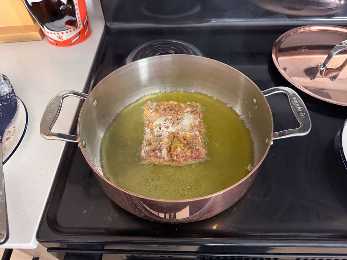 cube steak frying in oil in a copper rondeau